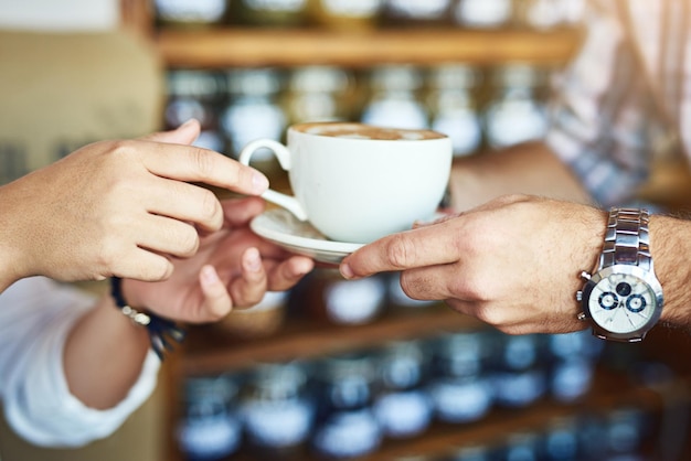 Donner du café à quelqu'un, c'est donner de l'amour Photo d'une femme méconnaissable recevant une tasse de café d'un serveur méconnaissable dans un café