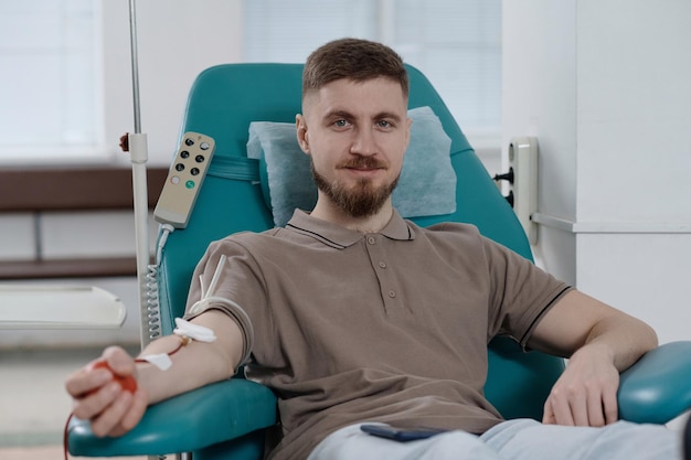 Un donneur de sang joyeux assis dans un fauteuil médical et regardant la caméra