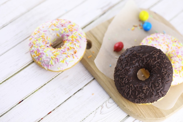 Donut au chocolat sur un fond blanc en bois et une dispersion d'ornements sucrés