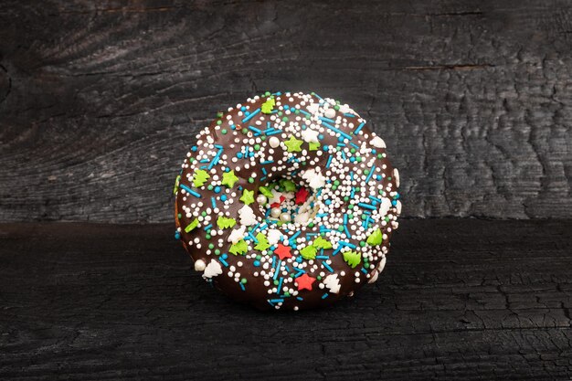 Donut au chocolat en glaçage saupoudré sur un fond sombre.