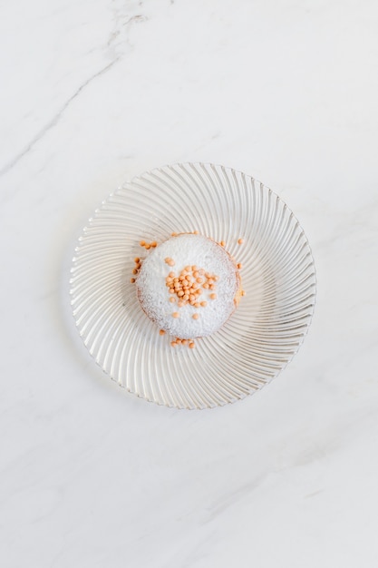 Donut décoré de vermicelles servi sur une table en marbre blanc