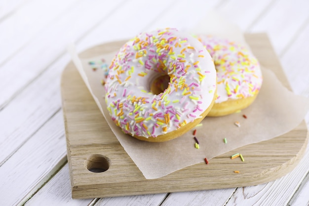 Donut sur un fond blanc en bois et une dispersion d'ornements sucrés