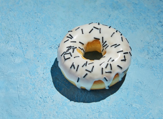 Donut Avec Glaçage Blanc Et Arrose Sur Fond Bleu.