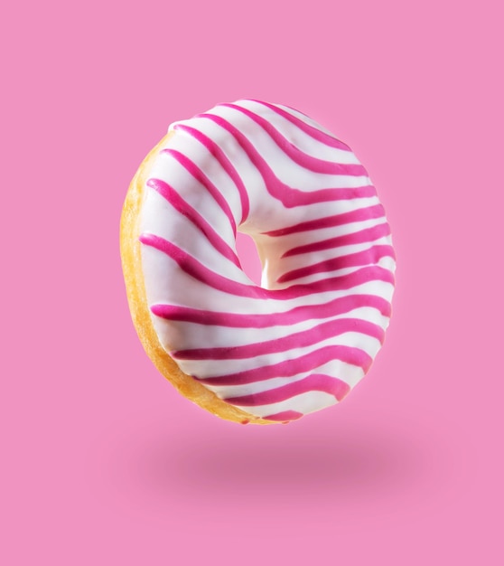 Donut glacé rose volant sur fond rose. Nourriture de concept de lévitation. Image colorée