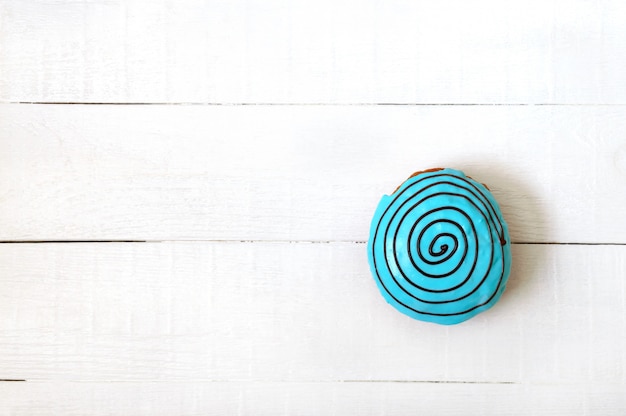 Donut en glaçure bleue sur fond de bois blanc