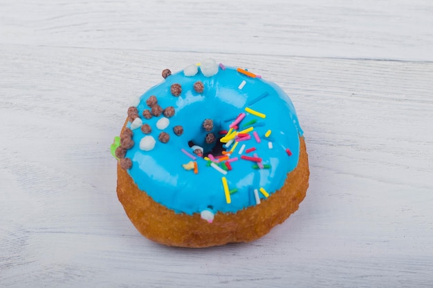 Donut avec glaçure bleue sur fond de bois blanc