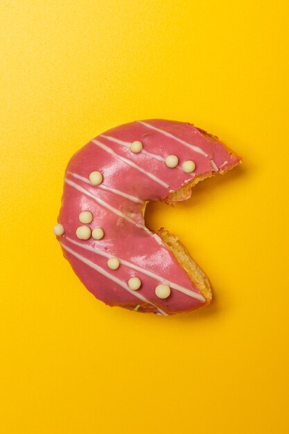 Donut de prune aux fraises mordu sur fond jaune