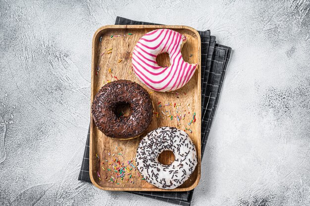 Donuts au chocolat, glacés roses et pépites Donut. Fond blanc. Vue de dessus.