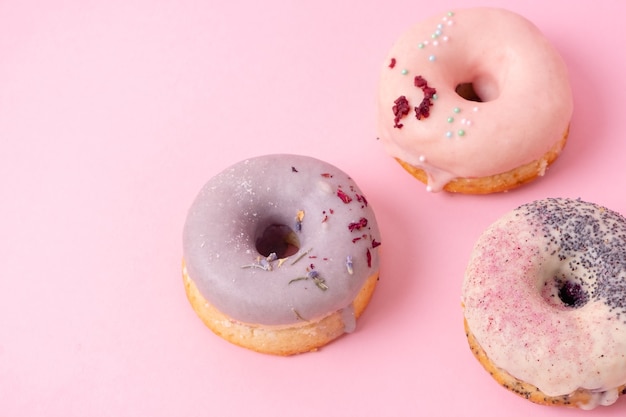Photo donuts avec glaçage pastel isolé sur fond rose clair
