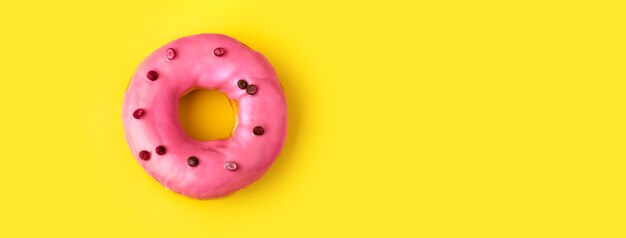 Donuts avec glaçage rose sur fond jaune