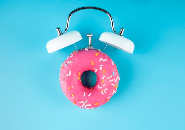 Donuts glaçure avec réveil sur bleu. Donuts réveil.