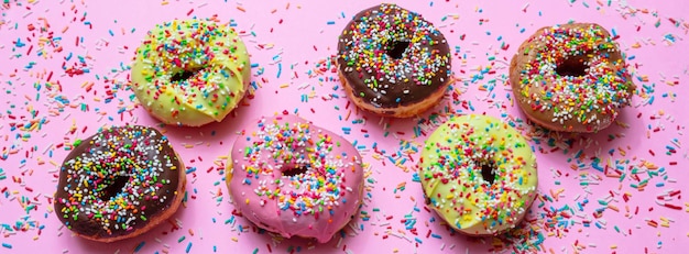Donuts avec pépites colorées sur fond rose vue de dessus