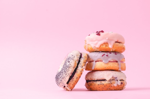 Photo donuts avec pile de glaçage pastel isolé sur fond rose clair