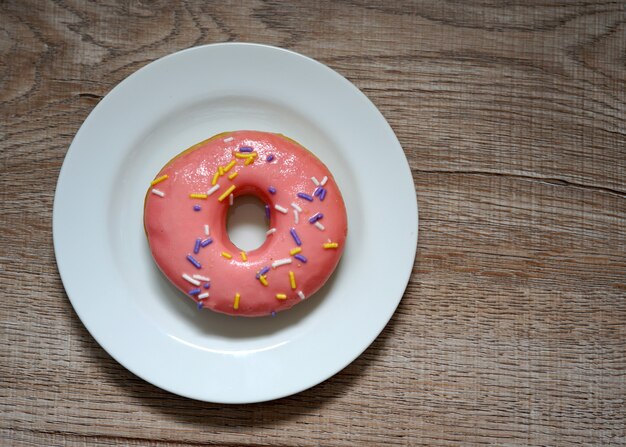 Donuts sucrés de couleur rose sur fond de bois