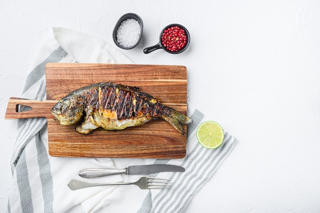 Dorade grillée ou poisson cru dorado sur planche à découper avec des ingrédients