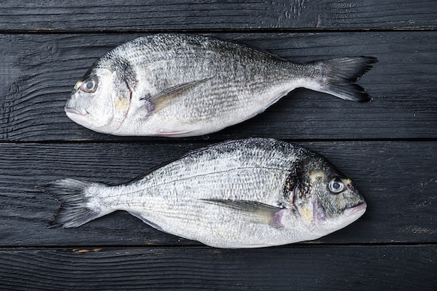 Dorado cru ou poisson dorade ob noir fond en bois vue de dessus.