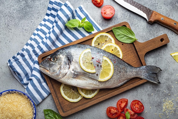 Dorado de poisson cru avec des ingrédients coupés au basilic frais au citron