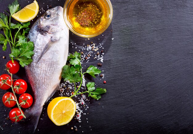 Dorado de poisson frais avec des légumes sur sombre, vue du dessus