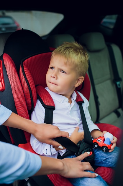 Dorlotez garçon, à, cheveux bouclés, séance, dans, siège auto enfant, à, voiture jouet, dans, mains