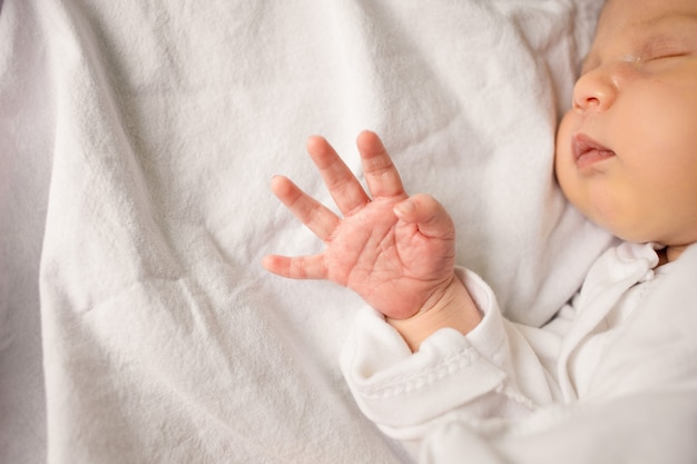 Dormir bébé nouveau-né dans une enveloppe sur une couverture blanche