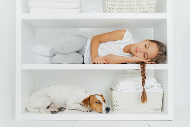 dormir petite fille se trouve sur une étagère blanche