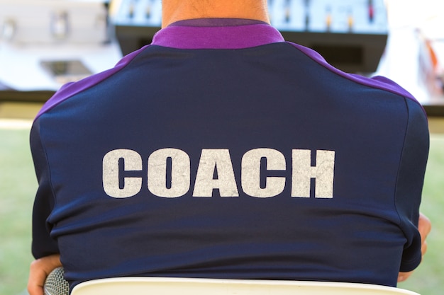 dos de la chemise de couleur bleu foncé d&#39;un entraîneur avec le mot Coach écrit sur