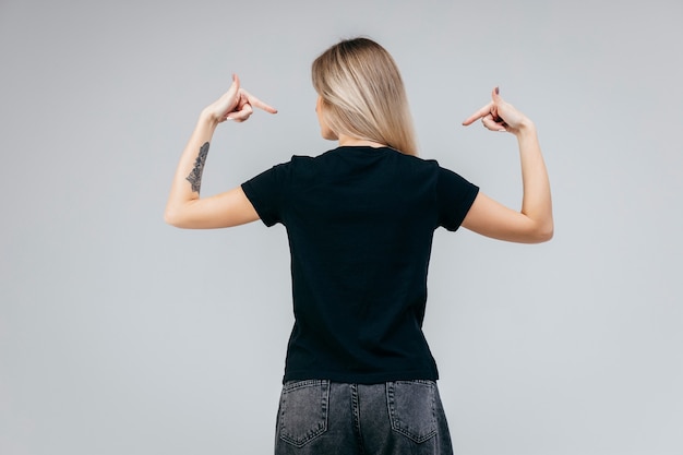 Dos de l'élégante fille blonde portant un t-shirt noir posant