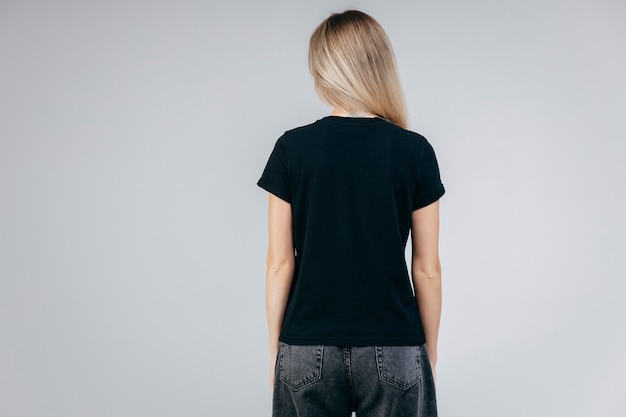 Dos de l'élégante fille blonde portant un t-shirt noir posant