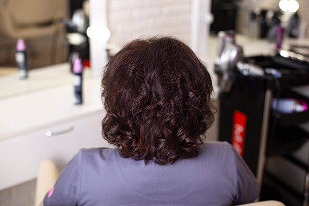 Dos femelle avec de courts cheveux bruns bouclés dans un salon de coiffure