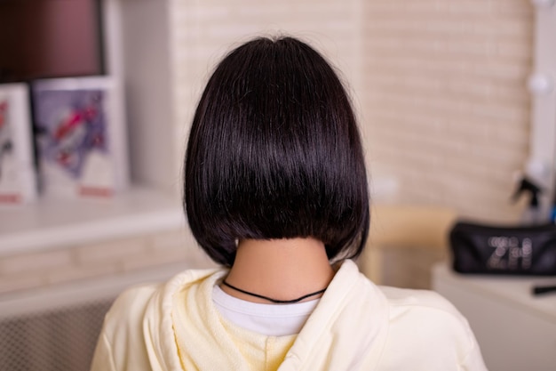 Dos féminin avec des cheveux bruns naturels courts et droits dans un salon de coiffure