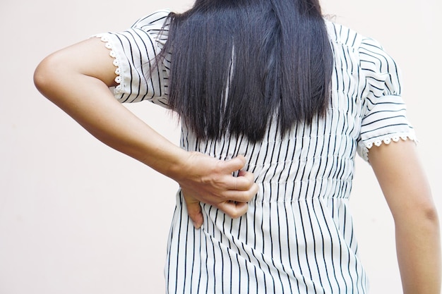 Dos de la femme blanche concept de maux de dos et de douleursFemme asiatique qui démange dans le dos