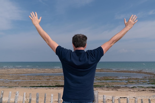 Dos d'homme avec les bras levés à la plage