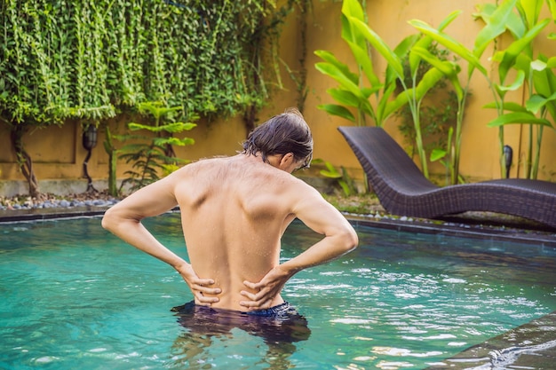 Le dos des hommes fait mal dans le contexte de la piscine La piscine aide à soulager les maux de dos