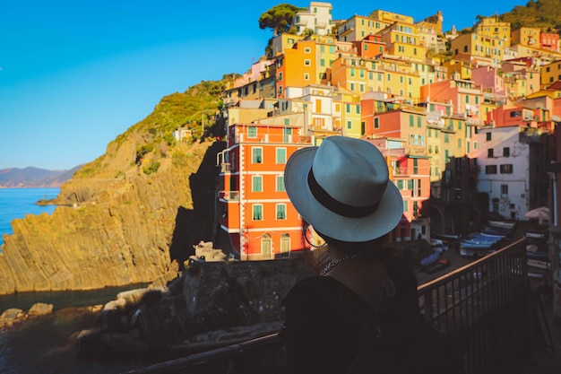 Dos d'une jeune femme élégante regardant une vue panoramique sur le village coloré de Riomaggiore Cinque Terre Italie