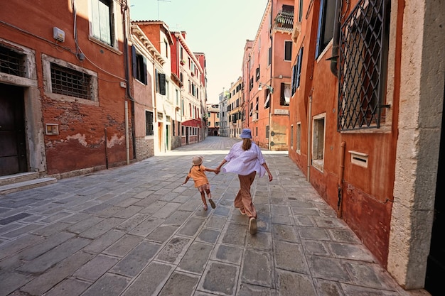 Dos de soeurs se tenant la main et courir dans la rue Venise Italie