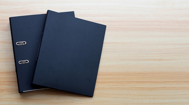 Dossiers de bureau noirs sur fond de texture en bois.