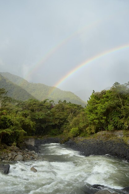 Double arc-en-ciel sur la forêt tropicale lors d'une journée d'été à Banos Equateur