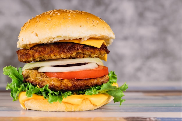 Double burger juteux avec des légumes sur la table.