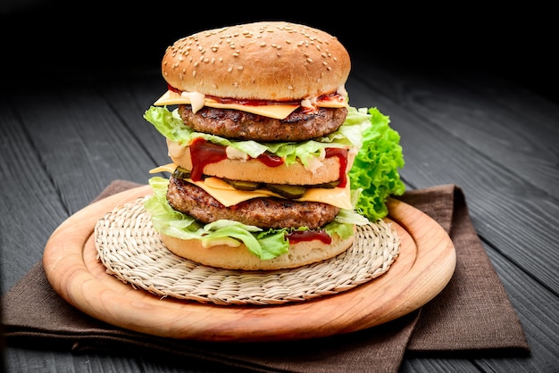 Un double cheeseburger de style classique avec deux galettes de bœuf, sauce, laitue, fromage, cornichons et oignons sur un petit pain aux graines de sésame