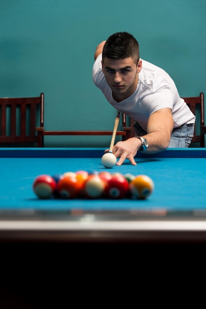 Doublure de jeune homme pour frapper la balle sur la table de billard