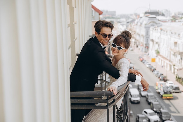 douce belle mariée et le marié se tenant la main se regardant près de l'ancien balcon de la clôture