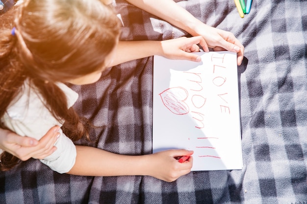 Douce et belle photo de fille allongée sur une couverture et dessin