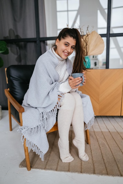 Douce femme relaxante avec une couverture couverte de boissons chaudes