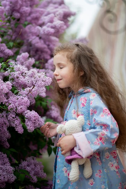 Une douce fille de cinq ans sur fond de lilas en fleurs Beauté de l'enfance