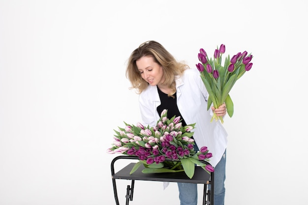 Une douce fille a recueilli un bouquet de différentes variétés de tulipes se dresse sur un fond blanc