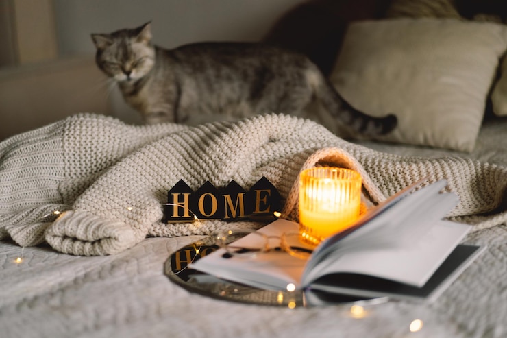 Photo douce maison bougie parfumée avec livre avec draps pliés en forme de cœur dans le lit
