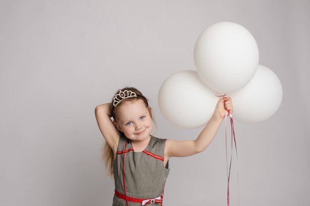 Photo douce petite fille avec des ballons à air chaud en studio.