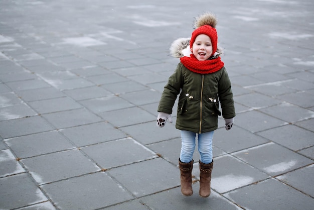 Photo douce petite fille drôle en tenue tendance marchant et dansant dans la rue s'amusant à sauter