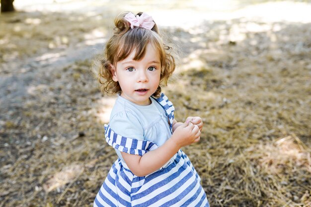 Douce petite fille à l'extérieur avec les cheveux bouclés