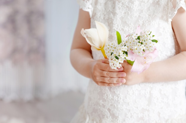 Douce petite fille tenant des fleurs dans les mains. Gros plan photo.